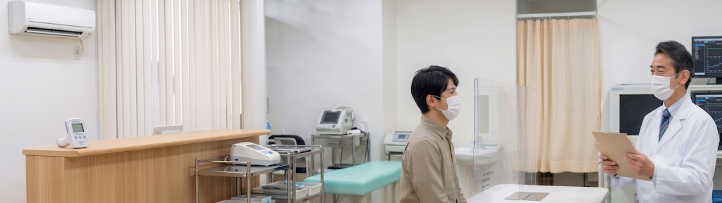 パーテーションで区切られた診察室で、医師の診察を受ける患者
